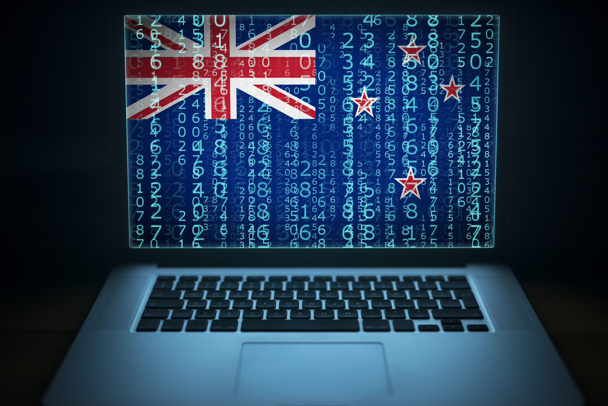 Binary code displayed on a laptop screen with a New Zealand flag in the background.